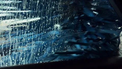Side view during an automated car wash cycle, showcasing water and brushes. Stock Footage 304019752
