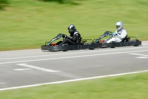 Side view of dynamic image of two competitive, moving fast, go-karts. Stock Photos