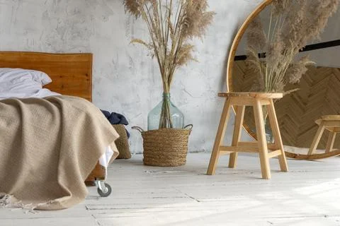 Side view of eco style loft bedroom with  wooden chair, mirror and pampas gra Stock Photos