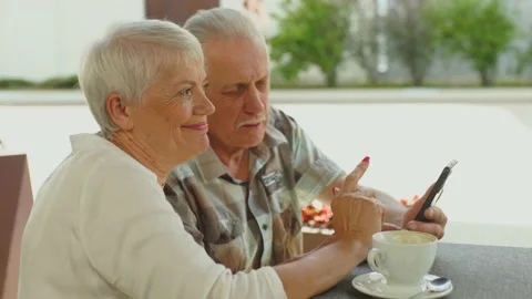 Side view of elderly couple discussing about further route in smartphone in cafe Stock Footage 209145639