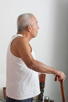 Side view of elderly man standing with cane showing mobility and visual imp.. Fotos Stock