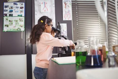 Side view of elementary schoolgirl using microscope at laboratory Stock Photos