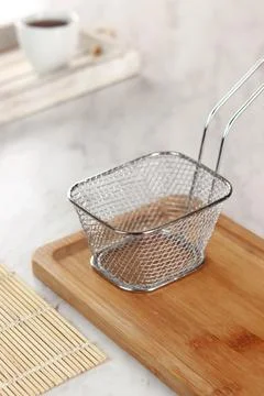 Side view of empty stainless steel wire chip serving basket isolated on woo.. Stock Photos