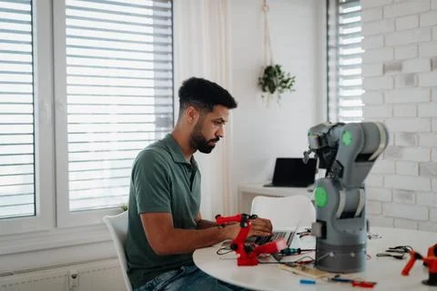 Side view of engineer building and programming a robotic arm at home. Fotos de archivo