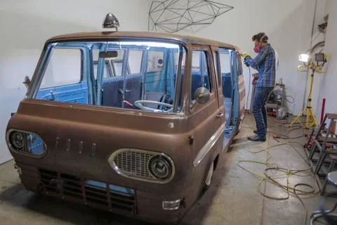 Side view of engineer polishing van with angle grinder in industry Stock Photos