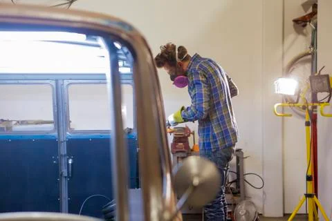 Side view of engineer polishing van with angle grinder in factory Stock Photos