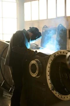 Side view of engineer in protective mask during process of arc welding Stock Photos