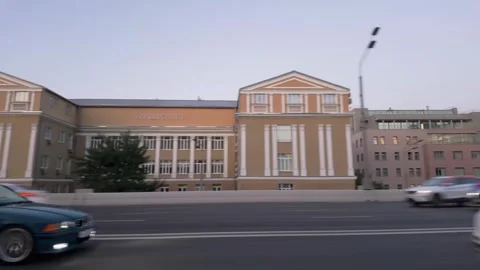 Side view: evening city traffic passing neoclassical building with headlights Stockbeeldmateriaal 339885657