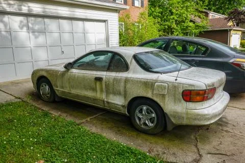Side view of an extremely dirty white car with a flat front tire Stock Photos