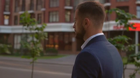 Side view of fair haired man walking along sidewalk Stock Footage 92056120