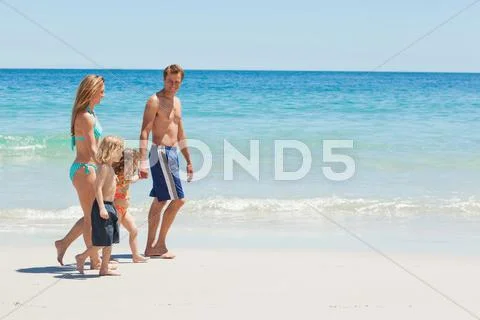 Side View Of A Family Taking A Walk At The Beach
