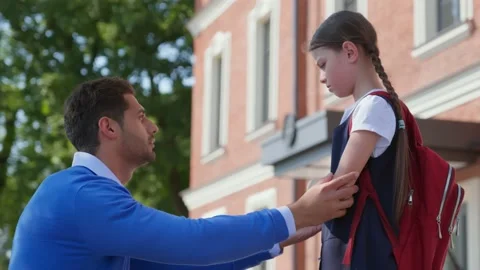 Side view of father cheering upset daughter outside school building Stock Footage 158385505