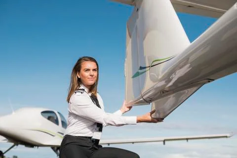 Side view of female engineer examining airplane parts while crouching on airport Stock Photos