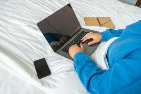 Side view of female hand using laptop on bed Stock Photos