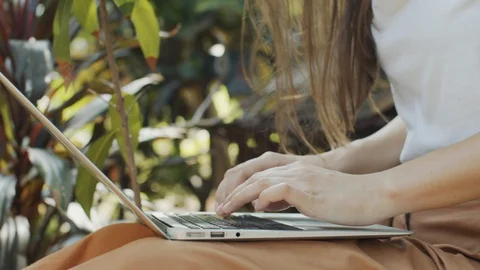 Side view of female hands typing laptop keyboard on green defocused background Stock Footage 129866102