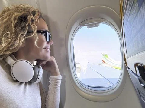 Side view of female passenger inside airplane flight looking outside the wi.. Foto stock