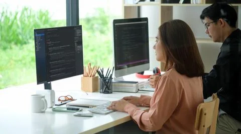 Side view of female programmer working with computer at modern office. Develo Stock Photos