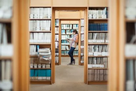Side view of a female student reading a book in library Stock Photos