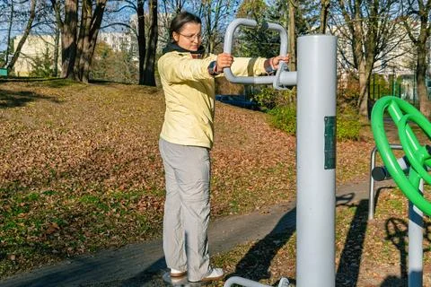 Side view of a female using a rotation disk trainer at a public outdoor gym Stock Photos