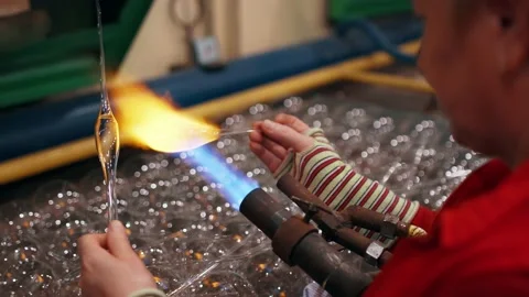 Side view of a female worker who heats a glass to blow a Christmas toy. Stock Footage 223210544