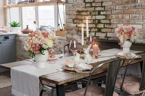 Side view on a festive table decor with glasses flowers and lit candles. Wedd Stock Photos