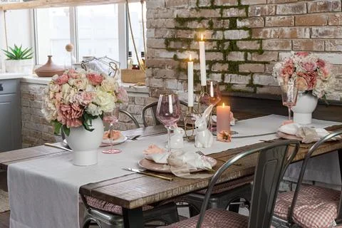 Side view on a festive table decor with glasses flowers and lit candles. Wedd Stock Photos