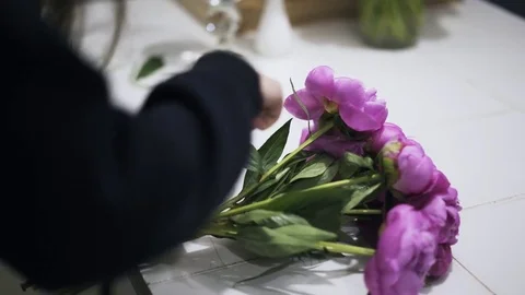 Side view of flower shop assistant tieing bunch of pink flowers 스톡 동영상 76202341