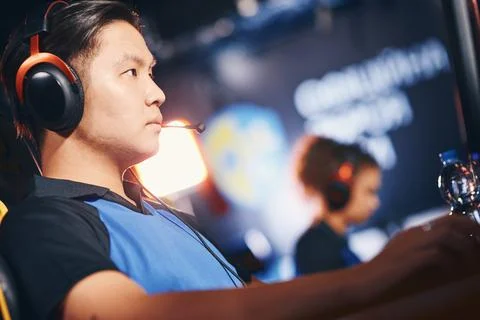 Side view of a focused asian guy, male cyber sport gamer wearing headphones Stock Photos