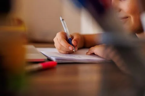 Side view of a focused little boy who is learning to write while doing his ho Stock Photos