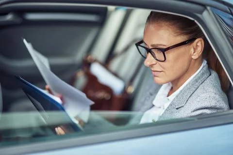 Side view of a focused middle aged business woman wearing eyeglasses analyzing Foto stock