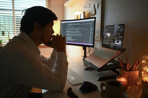 Side view of focused software developer programming on desktop computer 库存照片