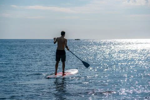 Side view foto of a man swiming and relaxing on the sup board. Sportive man in Stock Photos