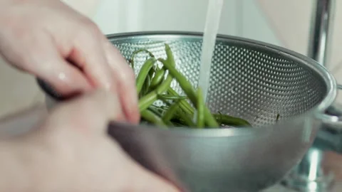 Side view of fresh French beans being washed under running water in a sink Stock Footage 343555594