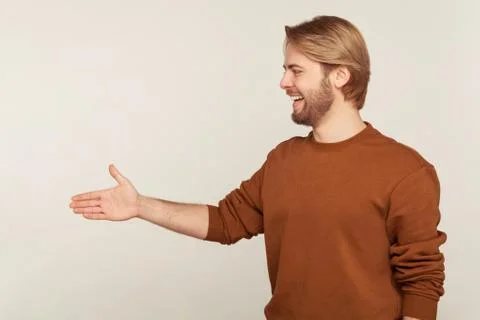 Side view of friendly hospitable bearded man in sweatshirt standing with outs Stock Photos