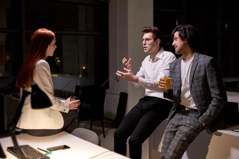 Side view on friendly office workers, colleagues having talk after hard working Stock Photos