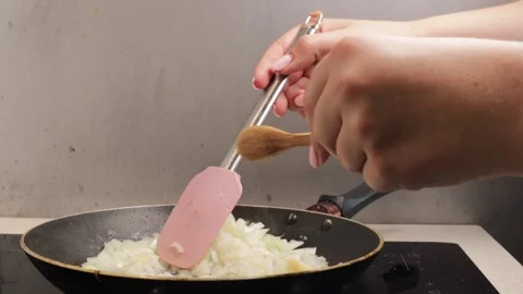 Side view of frying chopped yellow onion in pan using silicone spatula and Stock Footage 317107781