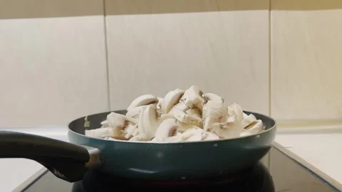 Side view of frying pan with mushrooms on glass electric stove 스톡 동영상 314967167