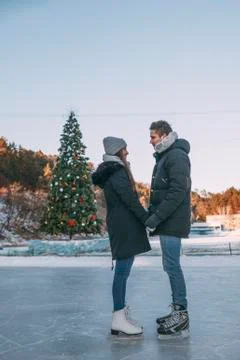 Side view full length of couple standing on ice rink against clear sky Stock Photos