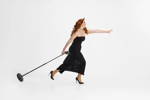 Side view full-length portrait of female singer carrying microphone and running Stock Photos