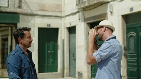 Side view of gay in hat taking photo of lover on camera outdoor 動画素材 164734741