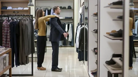 A side view general showcase of a clothing boutique consultant putting on a Stock Footage 135763890