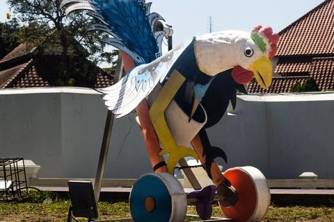 Side view of giant chicken push toy sculpture in city park square Stock Photos