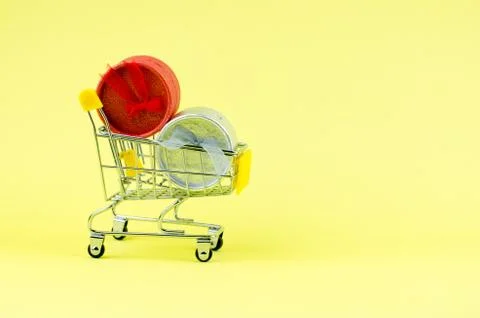 Side view of a gift box in and near a shopping cart on a yellow background Stock Photos