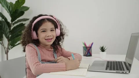 Side view of girl with headphone doing homework and looking at camera. Pedagogy. Stock Footage 270176497