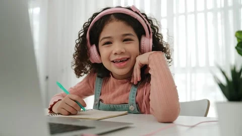 Side view of girl with headphone doing homework and looking at camera. Pedagogy. Stock Footage 270515762