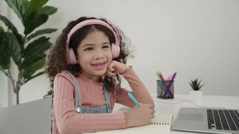 Side view of girl with headphone doing homework and looking at camera. Pedagogy. Stock Footage 277028519