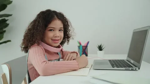 Side view of girl with headphone doing homework and looking at camera. Pedagogy. Stock Footage 283684849