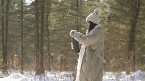 Side view. The girl opens a thermos with tea in a snowy forest Stock Footage 154205683