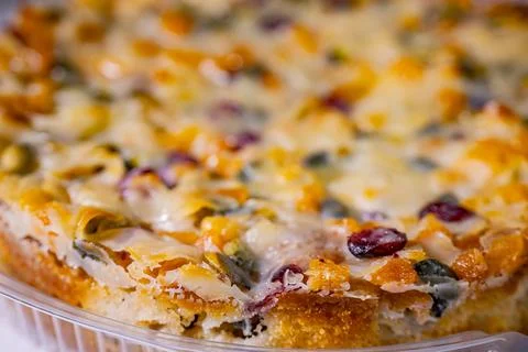 Side view of a glazed fruit and nut cake in a clear plastic container. 写真素材