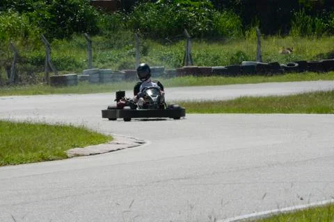 Side view of go-kart driver driving on race track on sunny day Stock Photos